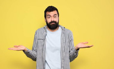 Handsome man with beard having doubts while raising hands