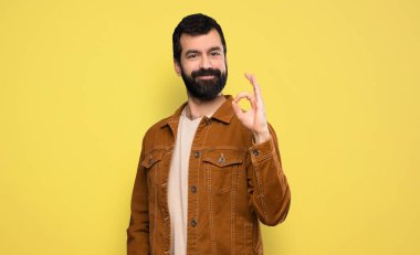 Sakallı yakışıklı adam parmaklarıyla işaret veriyor.