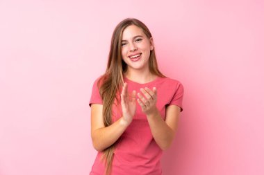 İzole edilmiş pembe arka planda genç sarışın kız alkışlıyor.