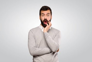 Yakışıklı adam, izole edilmiş gri arka plana bakarken şaşırmış ve şok olmuş.