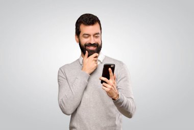 Yakışıklı adam gri arka planda düşünüp mesaj yolluyor.