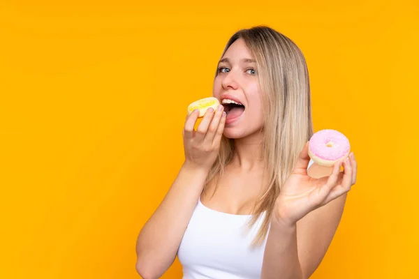 Jong Blond Vrouw Geïsoleerde Blauw Achtergrond Eten Een Donut — Stockfoto