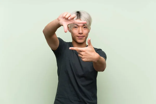 Mladý Asiat Izolovaném Zeleném Pozadí Zaostřující Tvář Rámcový Symbol — Stock fotografie