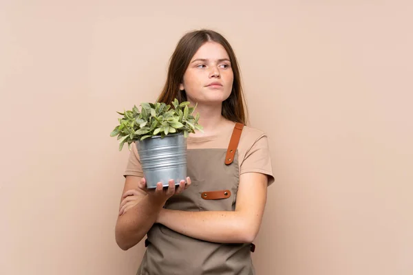 乌克兰少女园艺师抱着植物思考一个想法 — 图库照片
