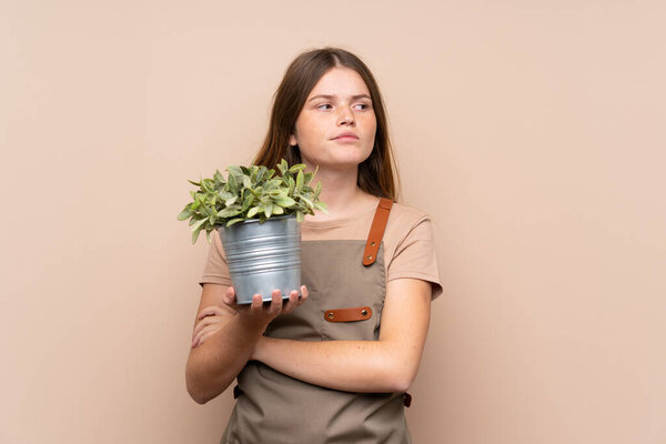 Украинская девушка-садовница держит в руках растение, думая об идее
