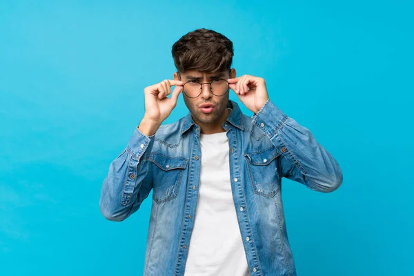 Junger Gutaussehender Mann Über Isoliertem Blauem Hintergrund Mit Brille — Stockfoto