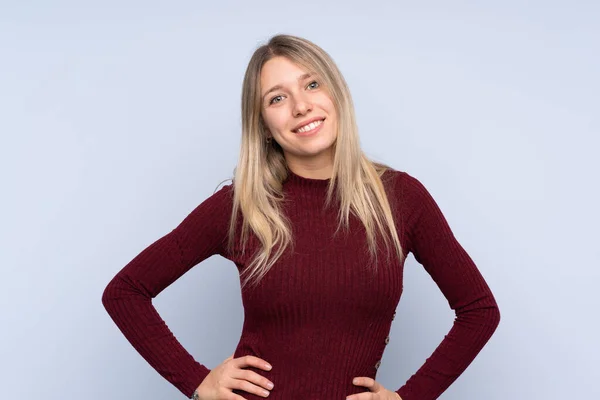 Young Blonde Woman Isolated Blue Background Posing Arms Hip Smiling — Stock Photo, Image