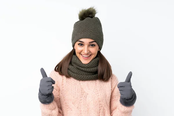 一个戴着冬帽的年轻姑娘 独立的白色背景 伸出一个大拇指来做手势 — 图库照片