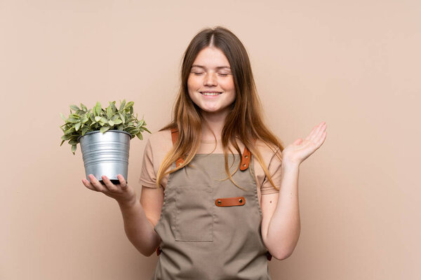 Ukrainian teenager gardener girl holding a plant laughing