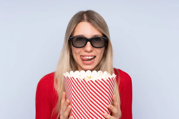 Młoda Blondynka Odizolowanym Niebieskim Tle Okularach Trzymając Duże Wiadro Popcornów — Zdjęcie stockowe