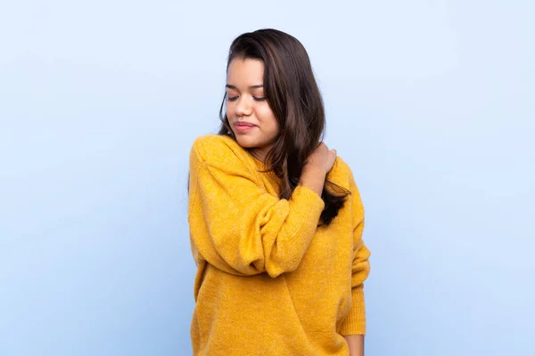 年轻的哥伦比亚女孩 穿着毛衣 背负着孤立的蓝色背景 由于付出了巨大的努力 肩负着疼痛 — 图库照片