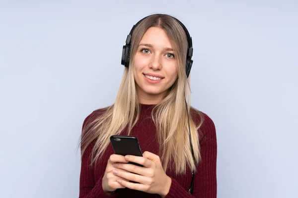 Giovane Donna Bionda Sfondo Blu Isolato Ascoltare Musica Con Cellulare — Foto Stock