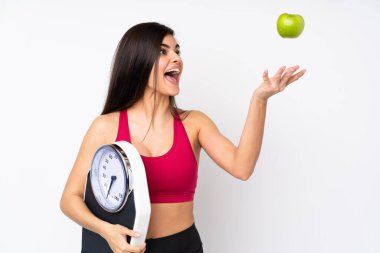 Tartı makinesi ve elmasıyla izole edilmiş beyaz arka planı olan genç bir kadın.