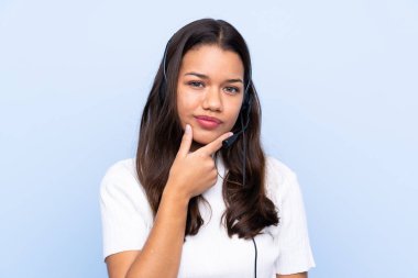 Genç tele pazarlamacı Kolombiyalı kadın izole edilmiş mavi arka planda bir fikir düşünüyor.