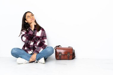 Genç bayan öğrenci yerde oturuyor ve yukarı bakıyor.