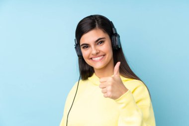 Soyutlanmış mavi arka planda müzik dinleyen genç bir kadın.