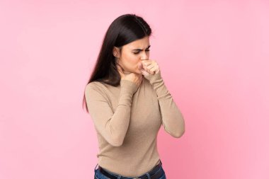 Soyutlanmış pembe arka planı olan genç bir kadın öksürük ve kötü hissetmekten muzdarip.