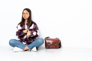 Genç bayan öğrenci yerde oturuyor ve geç kalma hareketini yapıyor.