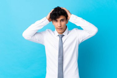 Genç Arjantinli iş adamı, mavi arka planda sürpriz bir yüz ifadesine sahip.