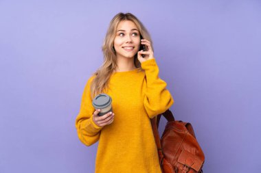 Mor arka planda izole edilmiş genç bir Rus öğrenci. Elinde kahve ve cep telefonu var.