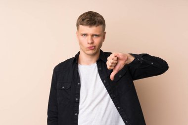 Genç yakışıklı adam baş parmağını aşağı gösteriyor.