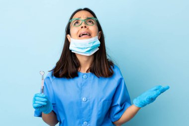 Genç, esmer, melez bir dişçi kadının, izole edilmiş arka planda aletleri tutması bunaltıcı.