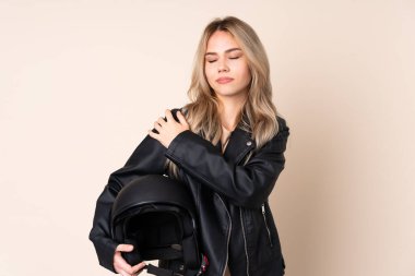 Motosiklet kasklı bir Rus kızı, bej arka planda izole edilmiş, omuz ağrısından muzdarip, çaba harcadığı için.