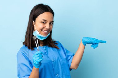Genç, esmer, melez, dişçi kadının elinde izole edilmiş arka planda parmak gösteren aletler var.