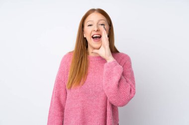 İzole edilmiş beyaz arka planı olan pembe kazaklı genç kızıl saçlı kadın ağzı açık bağırıyor.