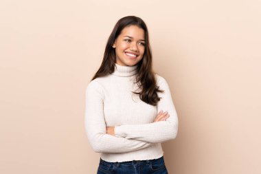 Young Colombian girl over isolated background with arms crossed and happy