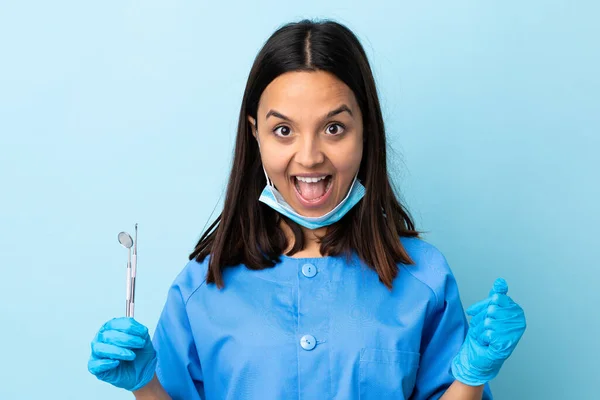 年轻的黑发混血女牙医拿着工具在与世隔绝的背景下庆祝获奖者的胜利 — 图库照片