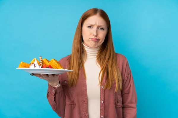 Jonge Roodharige Vrouw Houden Wafels Geïsoleerde Achtergrond Met Droevige Uitdrukking — Stockfoto