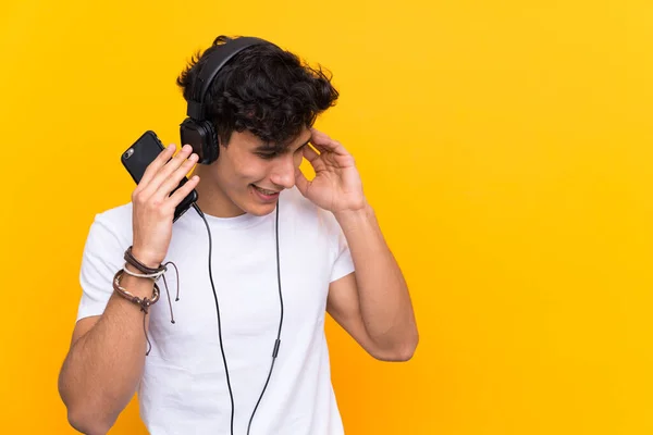 Νεαρός Αργεντίνος Ακούει Μουσική Ένα Κινητό Πάνω Από Απομονωμένο Κίτρινο — Φωτογραφία Αρχείου