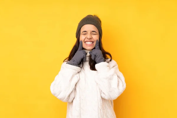 年轻女子头戴冬帽 黄底孤零零的 面带微笑 笑容满面 — 图库照片