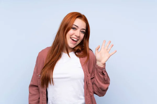 Redhead Έφηβος Κορίτσι Πάνω Από Απομονωμένο Μπλε Φόντο Χαιρετισμό Χέρι — Φωτογραφία Αρχείου