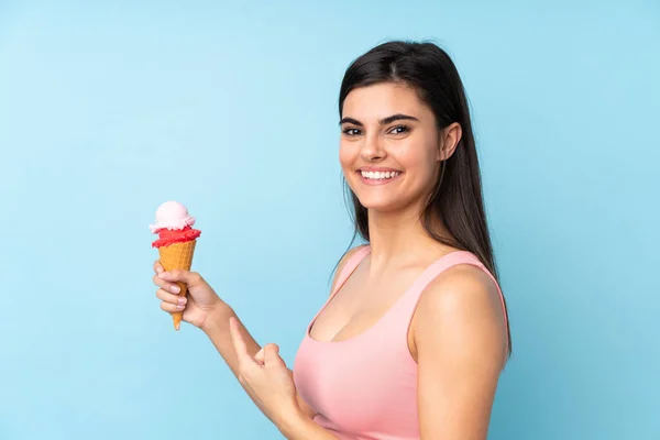 Jovem Segurando Sorvete Corneto Sobre Fundo Azul Isolado Apontando — Fotografia de Stock