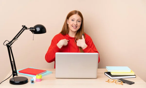 Young student woman in a workplace with a laptop with surprise facial expression