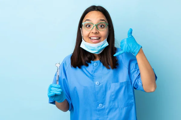 年轻的黑发混血女牙医拿着工具在孤立的背景下打手势和怀疑 — 图库照片