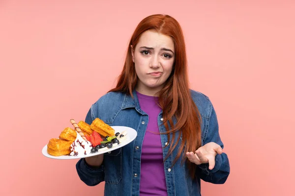 Redhead Teenager Girl Holding Waffles Isolated Pink Background Making Doubts — Stock Photo, Image