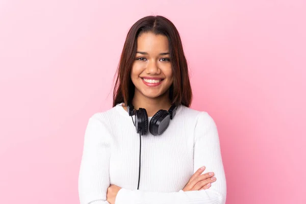 Young woman with earphones over isolated pink wall smiling a lot