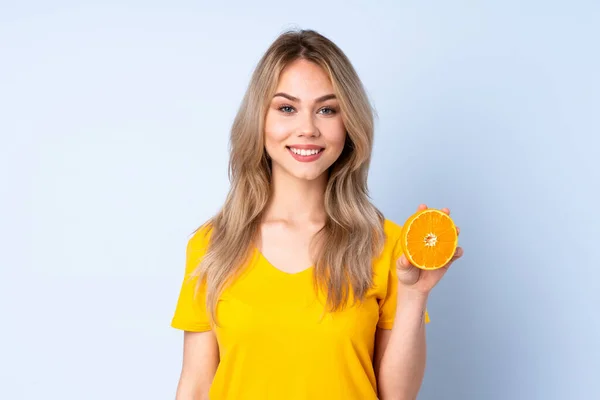 Tini Orosz Lány Kezében Egy Narancs Elszigetelt Kék Háttér Mosolygós — Stock Fotó