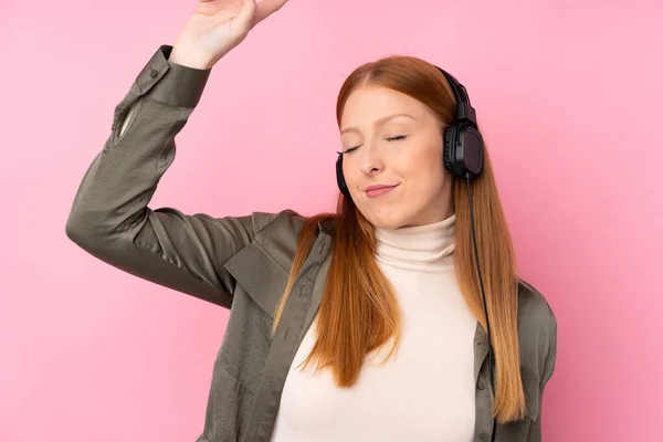 Νεαρή Κοκκινομάλλα Γυναίκα Πάνω Από Απομονωμένο Ροζ Φόντο Ακούγοντας Μουσική — Φωτογραφία Αρχείου