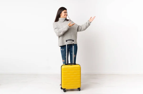 一个全身上下都是的女旅行家 提着一只手提箱 翻过孤立的白墙 向旁边伸出手来邀请她来 — 图库照片