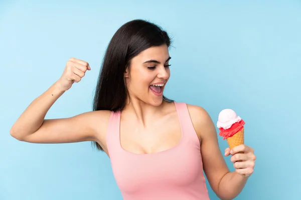 Молодая Женщина Держит Мороженое Корнета Изолированном Синем Фоне Празднуя Победу — стоковое фото