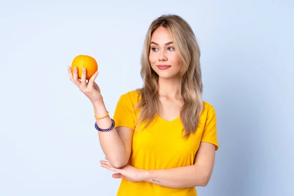 Teenager Russian Girl Holding Orange Isolated Blue Background — Stock Photo, Image