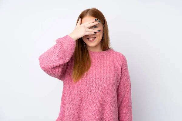 年轻的红头发女人 穿着粉色毛衣 用手捂住眼睛 面带微笑的孤立的白色背景 — 图库照片