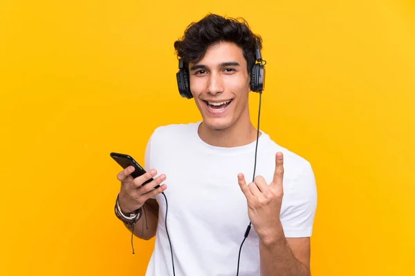 Jovem Argentino Ouvindo Música Com Celular Sobre Uma Parede Amarela — Fotografia de Stock