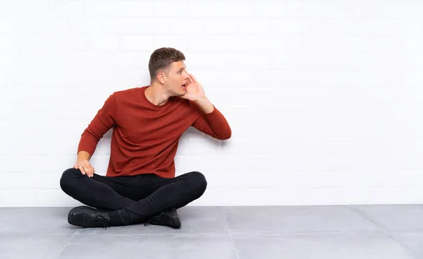 Mladý Pohledný Muž Sedí Podlaze Křičí Ústy Dokořán — Stock fotografie