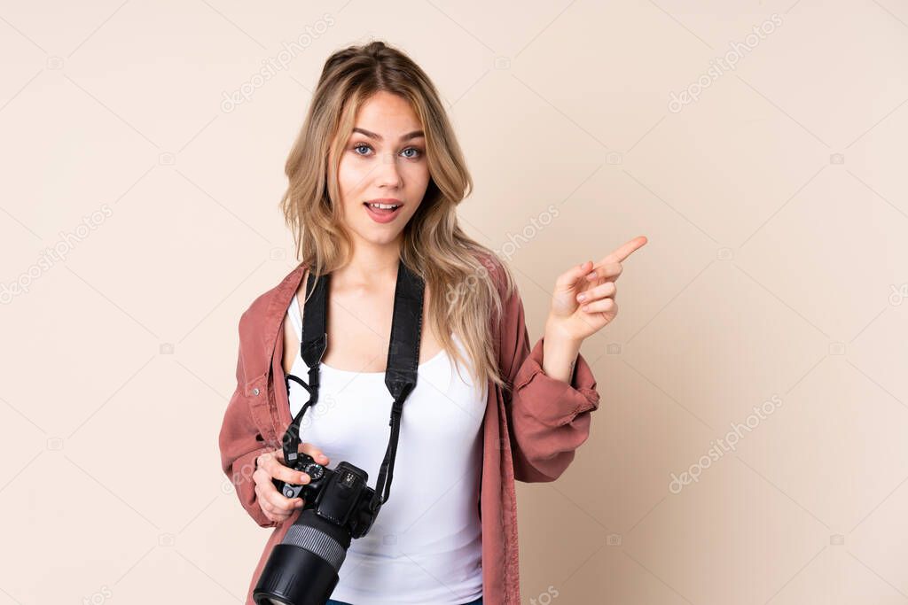 Young photographer girl over isolated background pointing finger to the laterals and happy