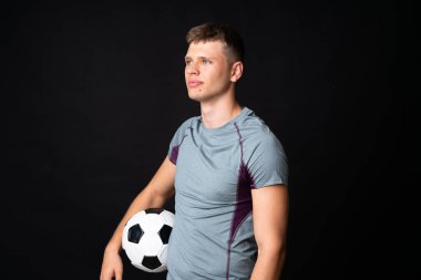 Yakışıklı genç futbolcu, izole edilmiş siyah duvarın üstünde.